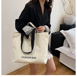 Close-up of stylish canvas tote bag with fashion lettering and black shoulder strap