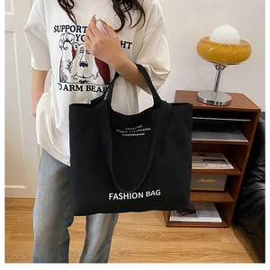 Detail shot of large black canvas tote bag with fashion text print and sturdy handles