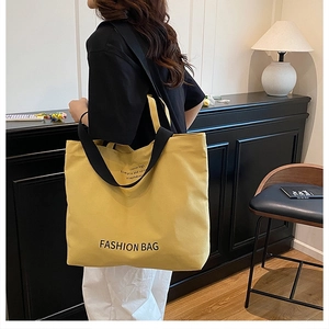 Detail of yellow canvas tote bag with black straps and fashion typography in modern room