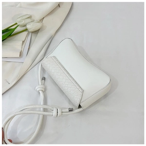 Detail of white crossbody bag featuring crocodile embossed texture and rope knot strap