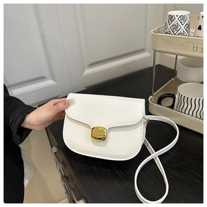 Détail du sac selle en cuir blanc avec boucle en métal doré et texture lisse élégante