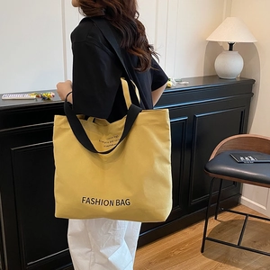 Vintage yellow canvas tote bag with black handles shown in a warm indoor lifestyle setting