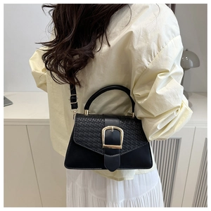 Nahaufnahme der schwarzen Ledertasche mit geflochtener Klappe und goldener Schnalle