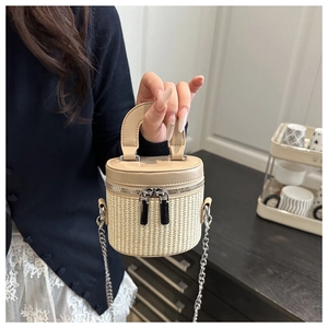 Detailed shot of woven straw bucket bag with faux leather trim and dual zippers