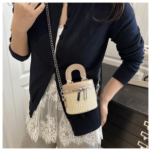 Close-up of beige woven bucket bag featuring dual zippers and brown leather trim details