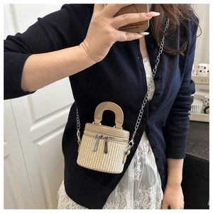 Mini cylindrical straw bucket bag with khaki leather trim and a fine metal chain strap
