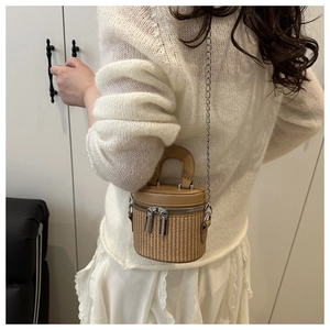 Detail view of woven cylinder bucket bag with double zippers and silver chain strap