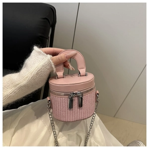 Detailed shot of a pink woven bucket bag with leather handles and silver chain strap
