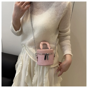 Detail view of a pink woven mini bucket bag with leather trim and gold chain strap