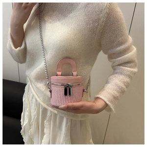 Detail of pink woven bucket bag featuring silver chain and dual zipper closure