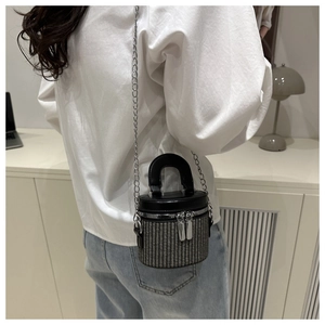 Detail of woven bucket bag with leather trim and silver chain strap shown on a model