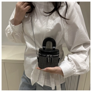 Macro detail of mini woven bucket bag with leather top handle and silver chain strap