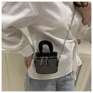 Detail of mini bucket bag showing mixed weave texture, double zippers and silver chain strap