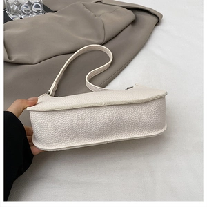 Detailed view of white lychee leather texture and side width of minimalist underarm bag