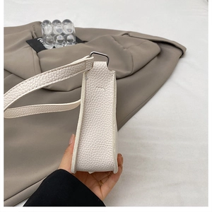 Detail view of the side width and lychee grain leather texture on this white underarm bag
