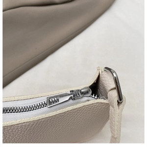 Detailed close-up of cream lychee texture leather with silver metal zipper hardware