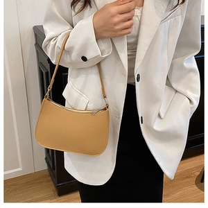 Close-up of vibrant yellow textured leather baguette bag worn with a white blazer