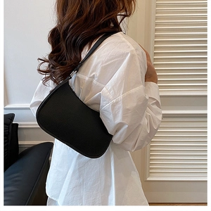 Close-up of black lychee grain leather hobo bag with silver metal buckle on female model