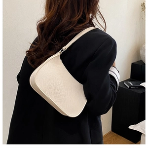 Close-up of off-white lychee pattern texture on a minimalist crescent underarm bag