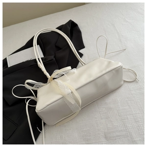 Dettaglio della borsa a spalla crema con pizzo bianco e fiocco in nastro beige