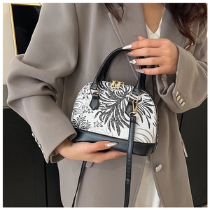 Detail of shell handbag with floral embroidery and black leather trim on grey blazer