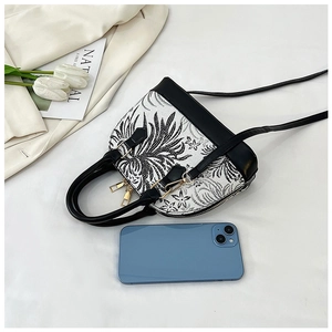 Detail view of shell crossbody bag with floral print and phone for size reference