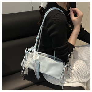 Dettaglio della borsa baguette azzurra con fiocco in pizzo e lacci decorativi sul lato