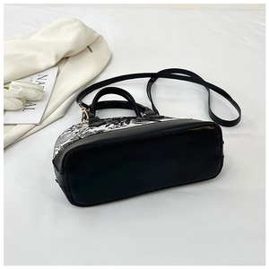 Detail of contrast embroidery shell bag with black leather handle and detachable strap