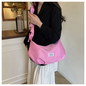 Close-up of pink nylon crossbody bag with ruffled strap and fashion woven label