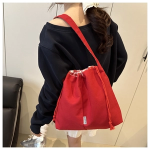 Détail du sac cabas en toile rouge avec fermeture à cordon et étiquette de mode