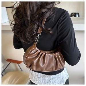 Gros plan d'un grand sac bandoulière plissé marron foncé de style vintage porté à l'épaule