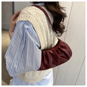 Detail of burgundy pleated leather shoulder bag showing texture and silver hardware