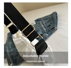 Close-up of golden metal adjustment buckle on black canvas strap with denim background