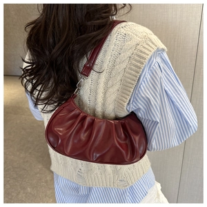 Detail of dark red vintage pleated cloud bag with shiny leather texture and shoulder strap