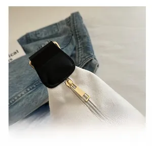 Detail of smooth gold zipper and black leather trim on minimalist white canvas bag