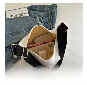 Detail showing internal capacity of the canvas crossbody bag with daily essentials inside