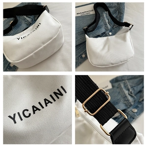 Detail view of white canvas crossbody bag with adjustable black strap and gold hardware