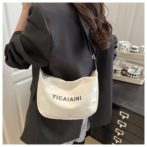 Detail of off-white canvas crossbody bag with wide black strap and brand print