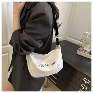 Detail of white canvas crossbody bag with black wide strap and YICAIAINI brand logo