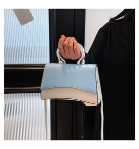 Detail of blue and beige square handbag featuring unique silver metal handle and strap