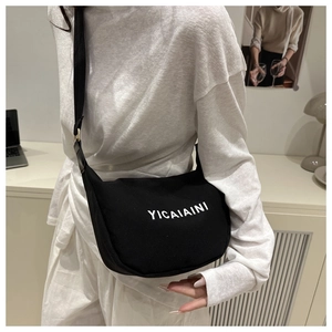 Detail shot of black canvas crossbody bag featuring white YICAIAINI lettering on a wide strap