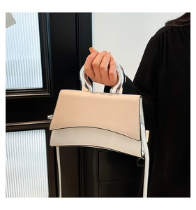 Detail of bicolor leather shoulder bag with curved bottom and silver metal handle