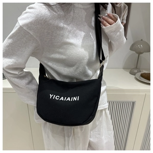Detailed side view of a black crescent canvas crossbody bag with wide shoulder strap