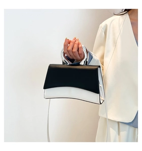 Detail of contrast leather handbag with curved base and industrial silver metal handle
