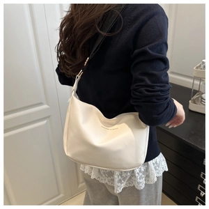 Detailed view of cream PU leather half-moon bag with adjustable wide strap and logo print