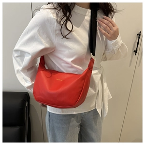 Detail of red crescent moon shoulder bag featuring golden logo and black wide strap