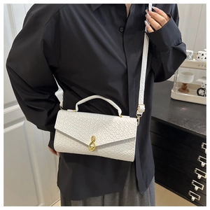 Close-up of white woven leather bag featuring a unique gold musical note metal buckle
