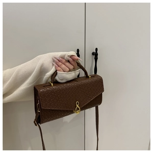Detail of dark brown woven texture bag featuring a unique gold musical note rotary lock