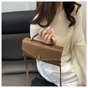 Detailed close-up of dark brown woven leather bag with unique gold musical note clasp