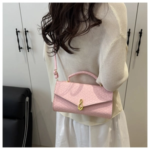Pink woven evening bag with crocodile texture and gold clasp worn as a crossbody bag